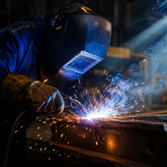 Professional welder wearing a protective helmet, performing precision metal fabrication in an industrial workshop, symbolizing the expertise found in our Welding Technology, Metallurgy, and Fabrication Reference Books collection.