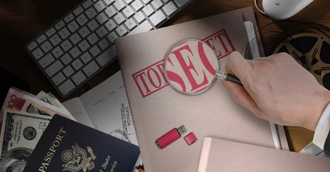 FBI counterintelligence and espionage image featuring confidential files, passport, thumb drive, computer, currency and magnifying glass representing modern intelligence investigations.
