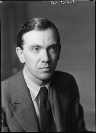 Black-and-white portrait photograph of British novelist Graham Greene in 1939, wearing a suit and tie. Historic image of the acclaimed author of The Power and the Glory, The Quiet American, and Brighton Rock. This photograph is in the public domain in the United States.