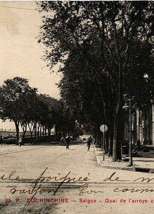 Historic postcard view of the Chinese Arroyo waterfront in Saigon, French Indochina (now Ho Chi Minh City, Vietnam), featuring a tree-lined boulevard, colonial-era buildings, pedestrians, and canal-side activity along the Arroyo Chinois. This vintage image is in the public domain in the United States.